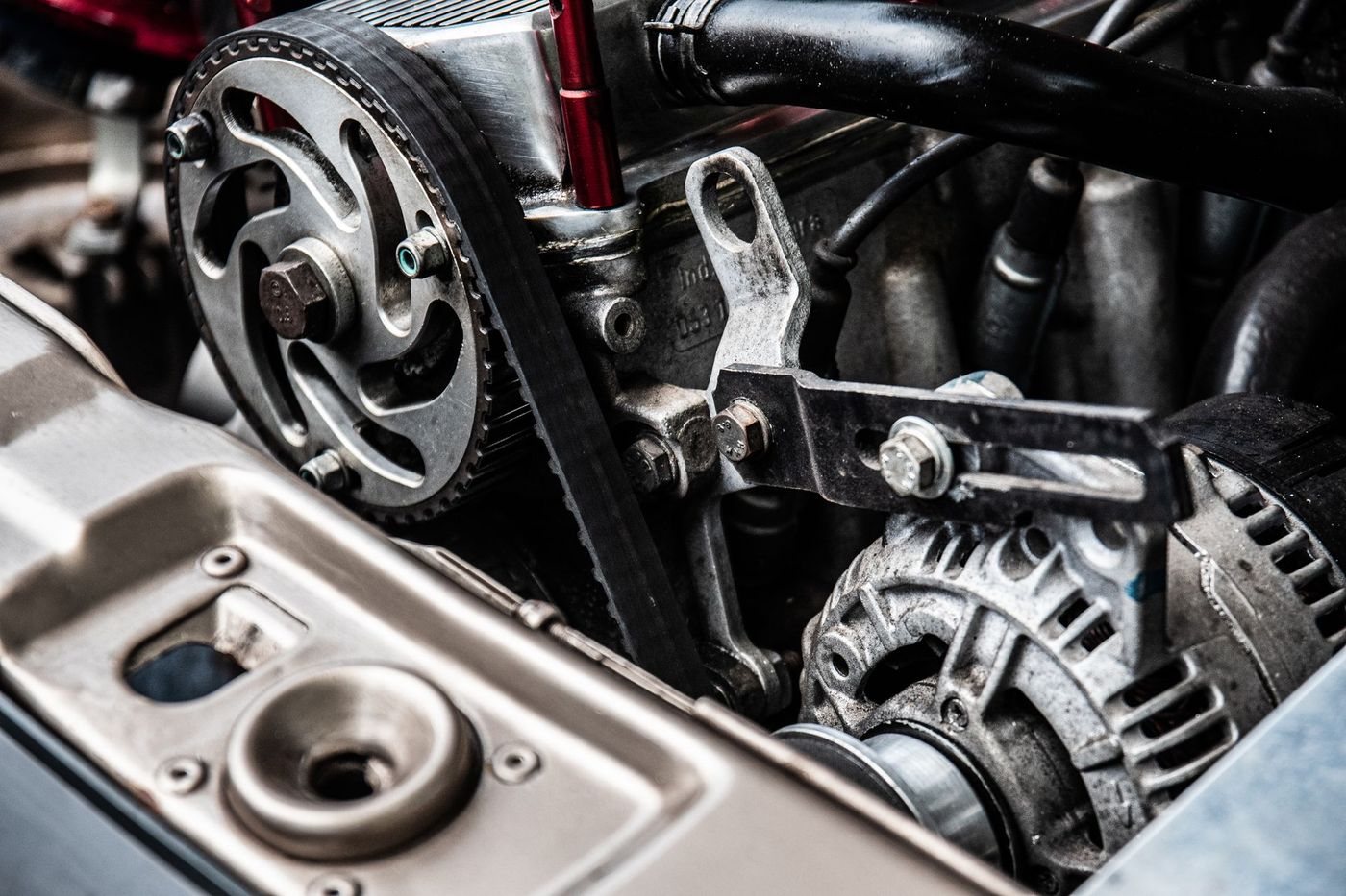 Close-up of a toothed drive belt on its pulley with hoses behind it