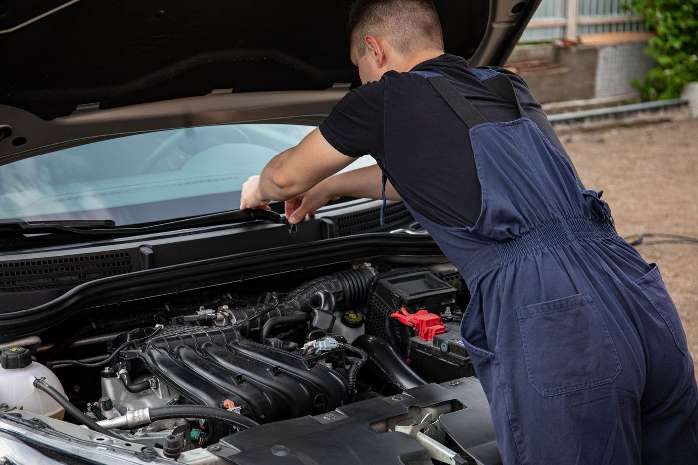 A mechanic leaning into an open engine bay outdoors — a stock photograph, not JM Mobile Mechanic's own work